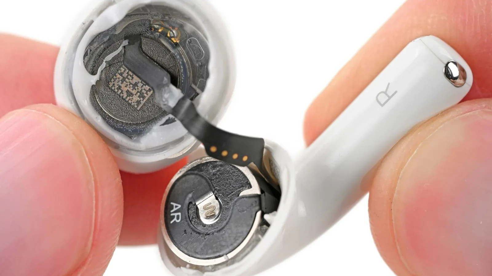 The inside of an AirPods 5 earbud with its small round battery exposed